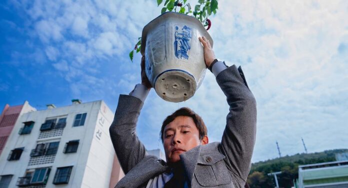 No Other Choice star Lee Byung-hun holds a chili pepper tree over his head
