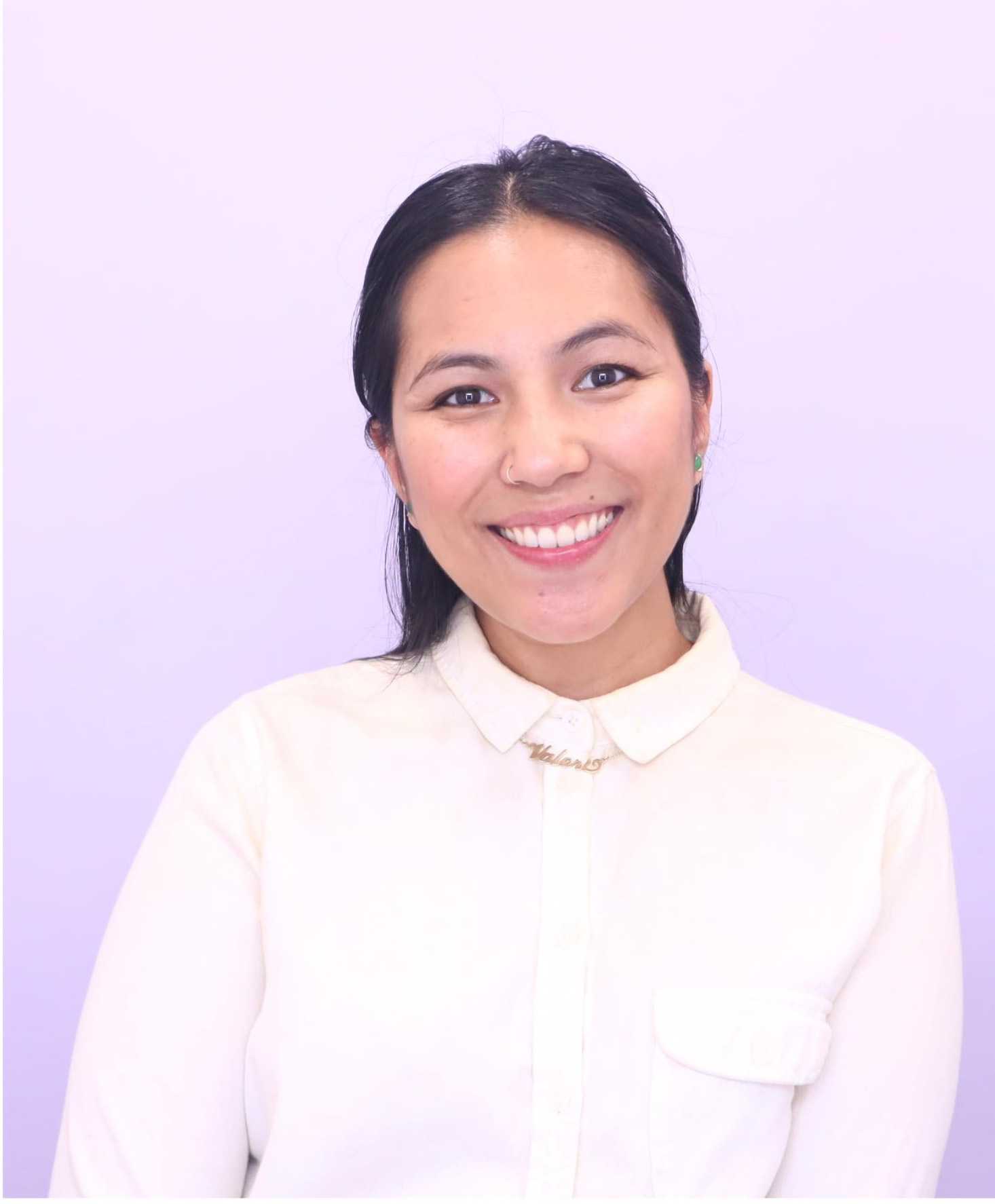 portrait of WEBTOON Editor Valeri Alemania. standing in front of a light purple to dark purple gradient backdrop wearing a light pink dress shirt with a smile. 
