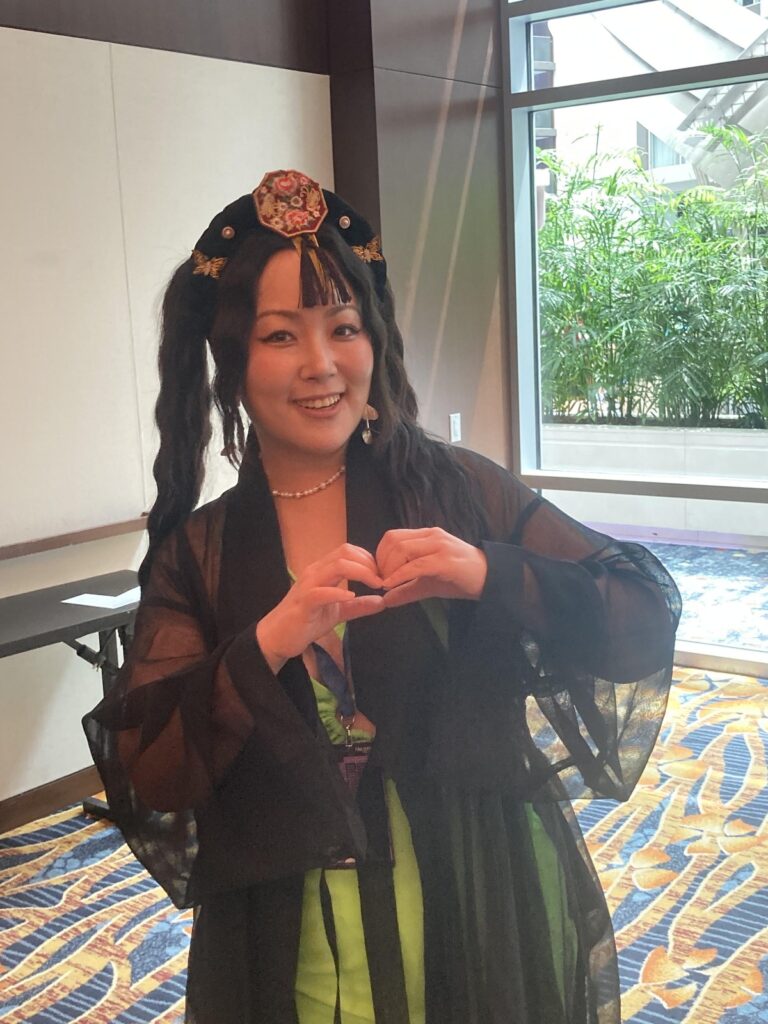 A photograph of Moon Taeyeon. She is making a heart symbol with her hands; her hair is braided.